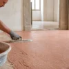 Artigiano liscia un pavimento continuo in cocciopesto color terracotta