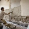 Muratore applica intonaco deumidificante su una parete umida
