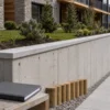 Muro in cemento tra giardino privato e camminamento condominiale con elementi della barriera in legno