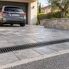 Tecnico controlla la griglia di una canaletta carrabile su un vialetto pavimentato