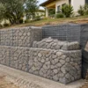 Muro in gabbioni metallici con pietrame, base e geotessile durante il montaggio
