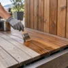 Artigiano applica olio per esterni su una pedana in legno con bordi drenanti