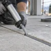 Operatore con guanti applica sigillante in un giunto tra lastre di calcestruzzo
