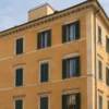 Facciata ocra di un edificio storico illustrativo con persiane e ponteggio laterale